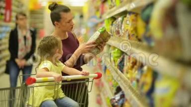 母亲和女儿在超市购物。 他们正在买早餐片。 一个女儿坐在超市